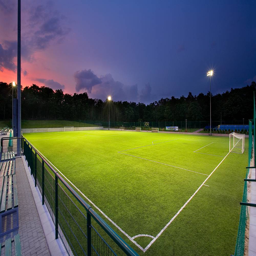 Fußballplatz bei Nacht, professionell und gleichmäßig ausgeleuchtet von leistungsstarken LED-Flutlichtstrahlern.