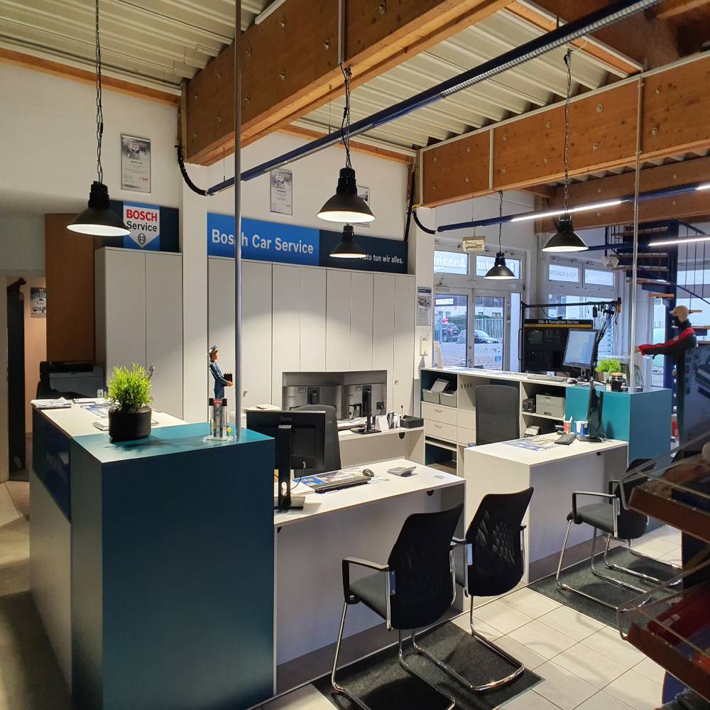 Helle Rezeption eines Bosch Car Service, beleuchtet durch moderne LED-Hallenstrahler, die eine freundliche und professionelle Atmosphäre schaffen.