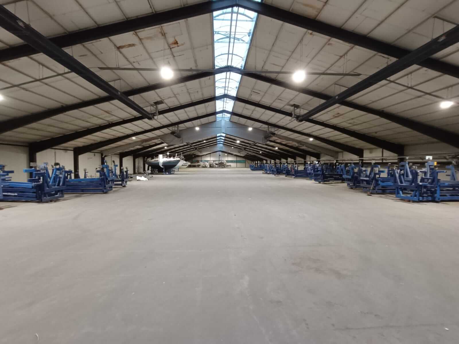 Innenansicht der Schiffslagerhalle am Sporthafen Kiel mit LED-Hallenstrahlern im eingeschalteten Zustand, die den Raum erhellen.
