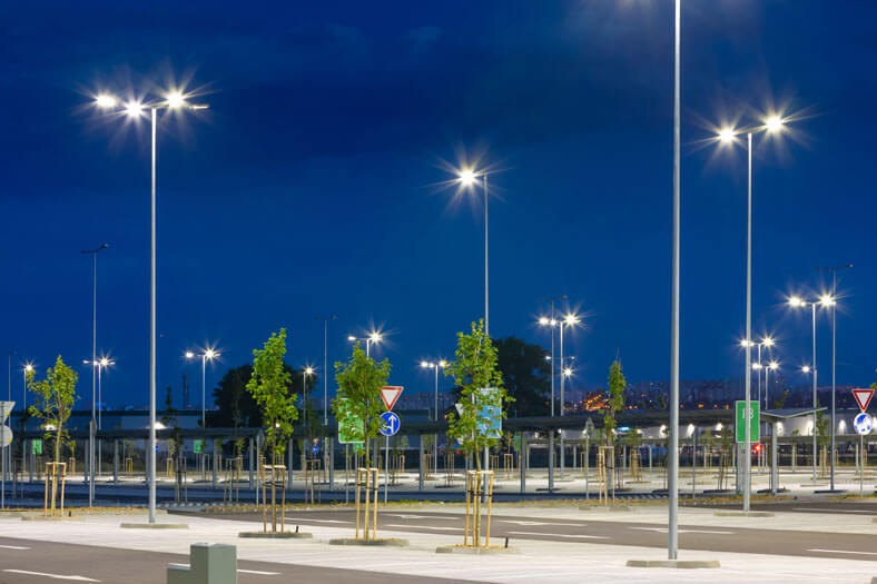 Großer Parkplatz bei tiefblauem Himmel, der gleichmäßig durch moderne LED-Straßenlaternen beleuchtet wird, um die Sicherheit zu gewährleisten.
