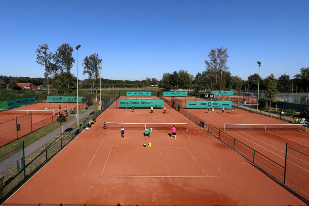 Tennisspieler auf der Anlage des VfL Grafenwald bei Tag, im Hintergrund die umgerüsteten LED Flutlichtmasten.